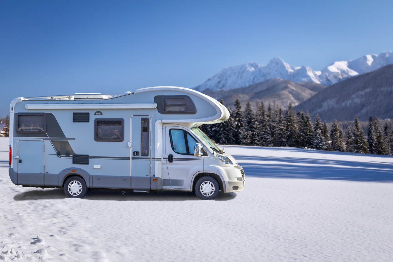 camper rv parked on snow with mountains in the background how to prepare your rv for winter