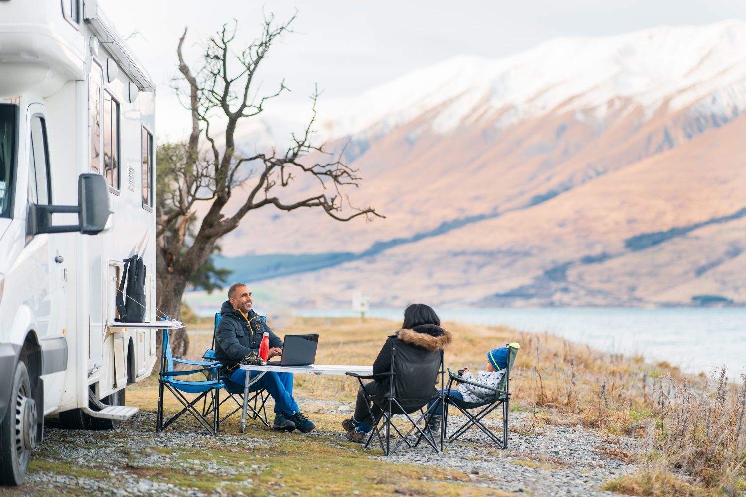 A travelling family enjoying outside next to their RV in a beautiful beach along with working remotely get paid to travel