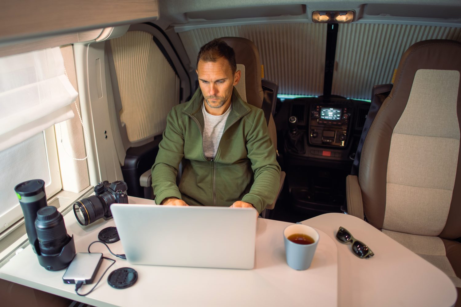 Man Working Remotely Getting Paid to Travel From Camper Van Using Internet Connection. Work and Travel Possibilities Theme