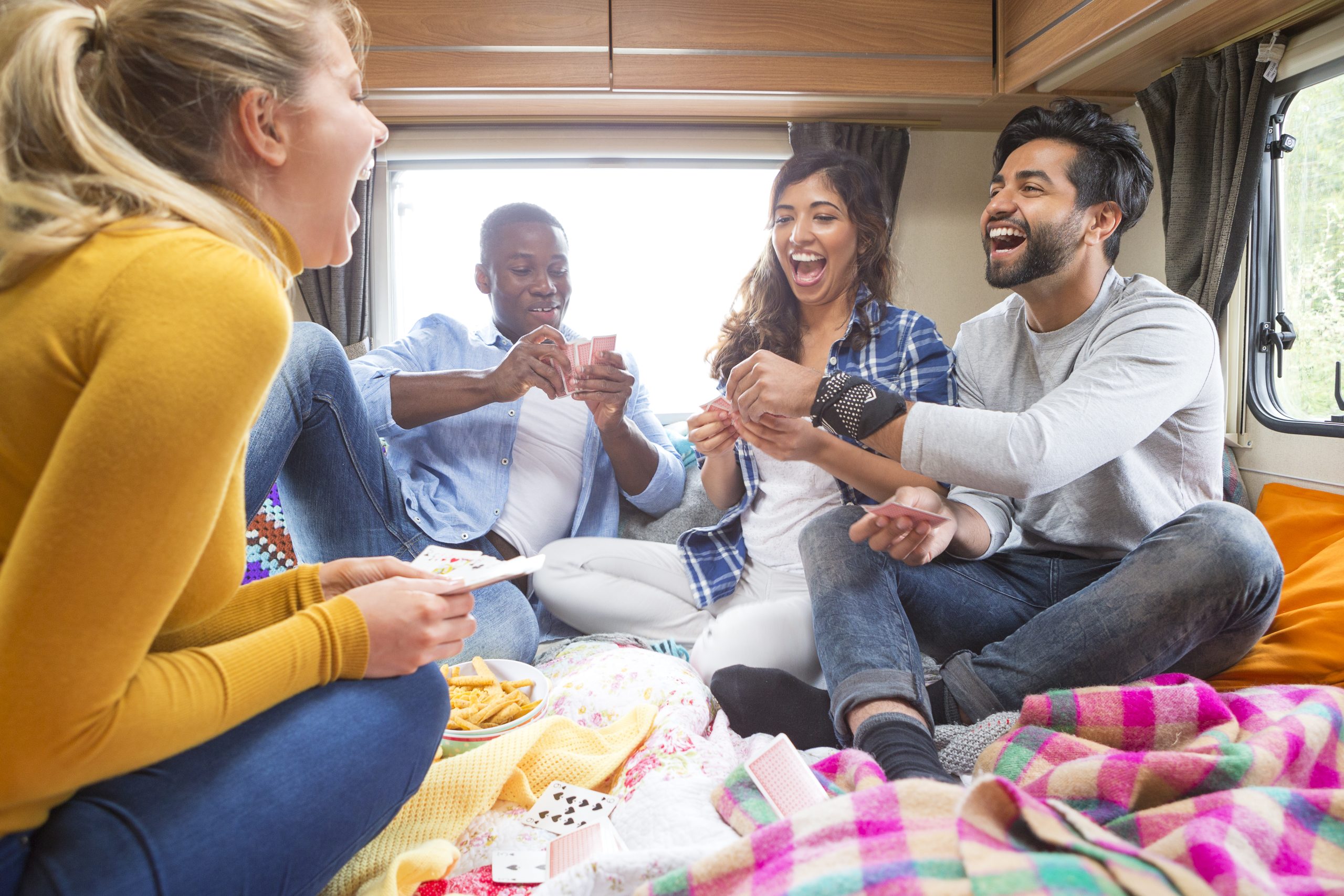Group of friends having fun playing cards in a motorhome or rv how to have fun on a motorhome trip