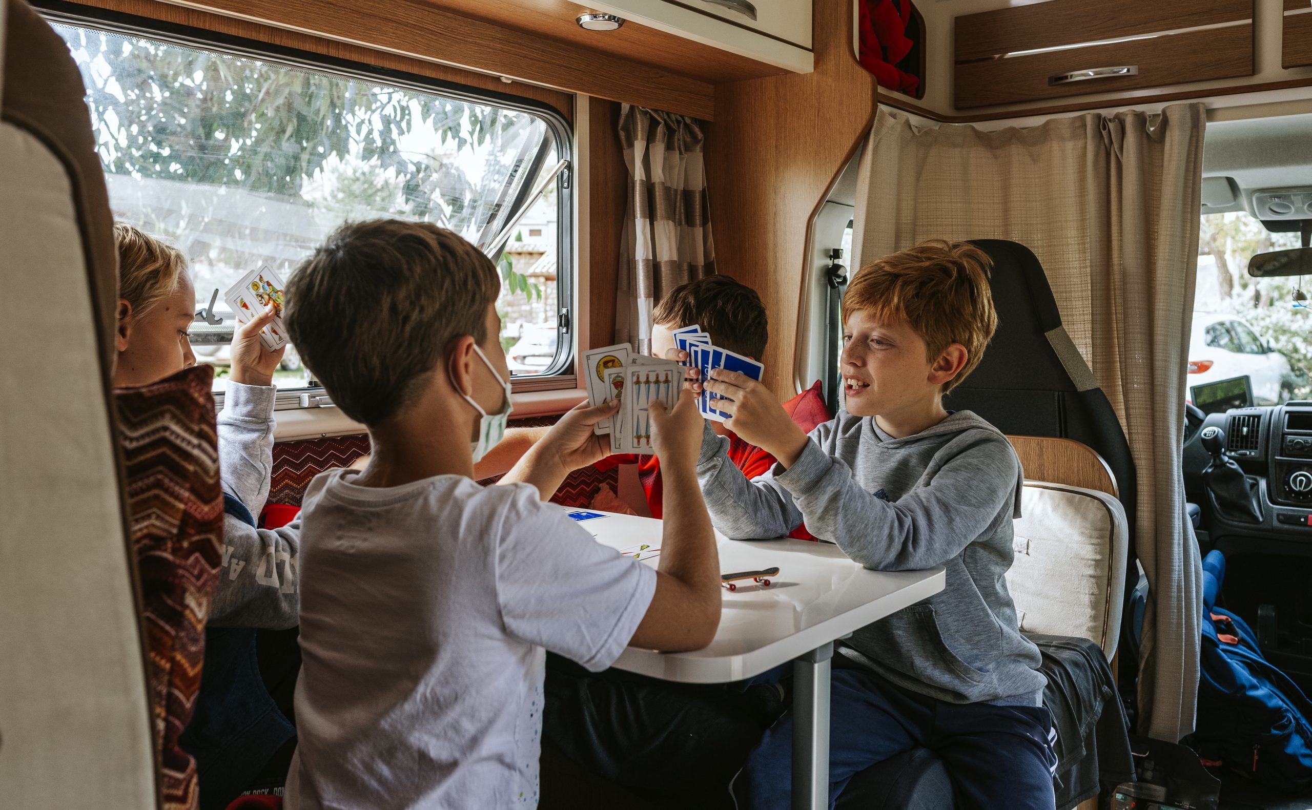 Children playing cards in an rv motorhome trailer on road trip camping